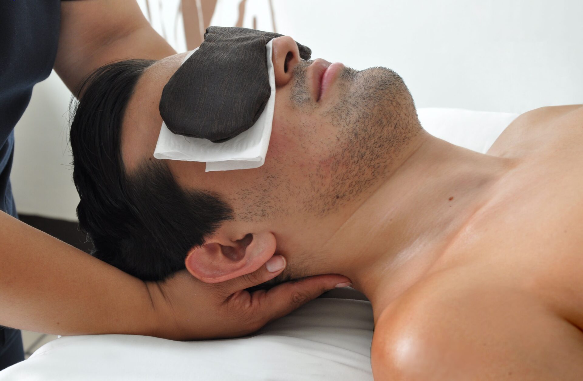 A Paxio therapist massaging the neck of a guest wearing an eye mask